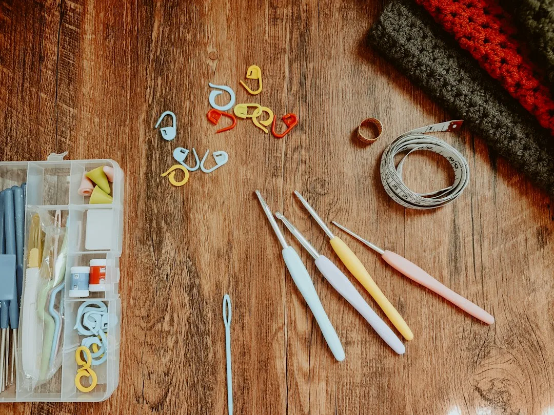 Crochet project in progress with yarn skeins, hooks and stitch markers on a table