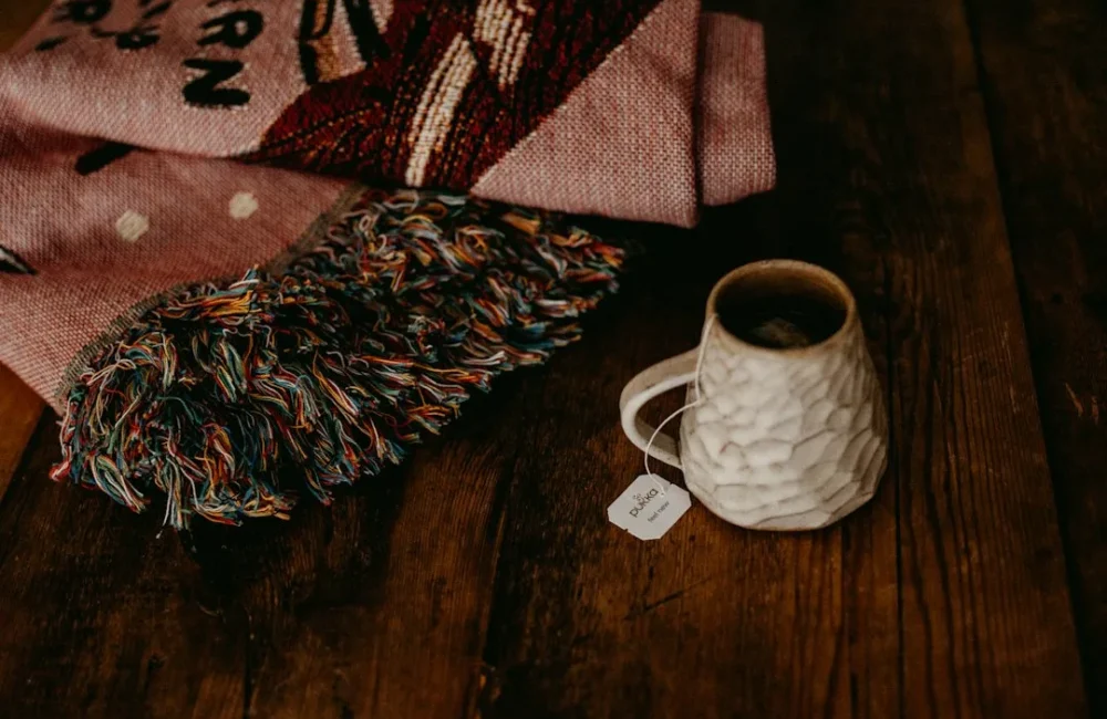 Warm socks, slippers, a blanket and a mug arranged for a cold day indoors