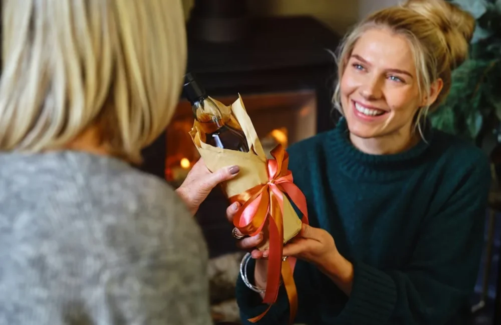Woman giving a wrapped Christmas present to another woman