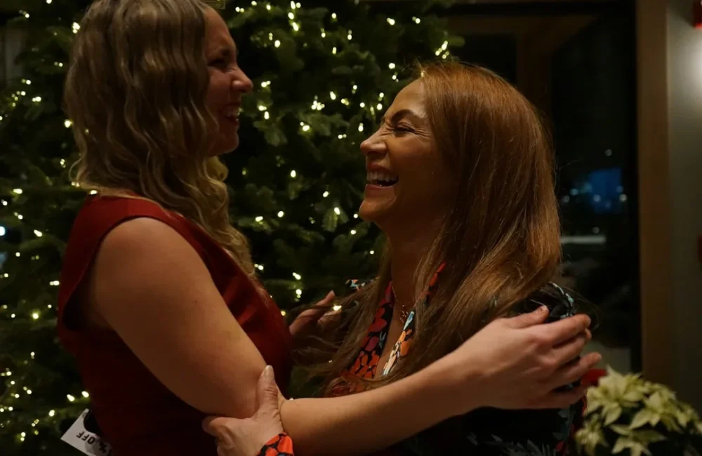 Two women standing together beside a Christmas tree