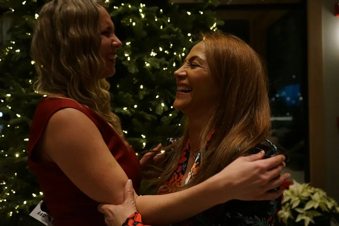 Two women standing together beside a Christmas tree