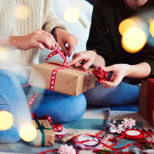 Person wrapping a gift with an uncertain, thoughtful expression reflecting gift-giving anxiety