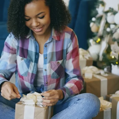 A young woman opening an elegant gift at a family gathering, illustrating gifts for a daughter-in-law