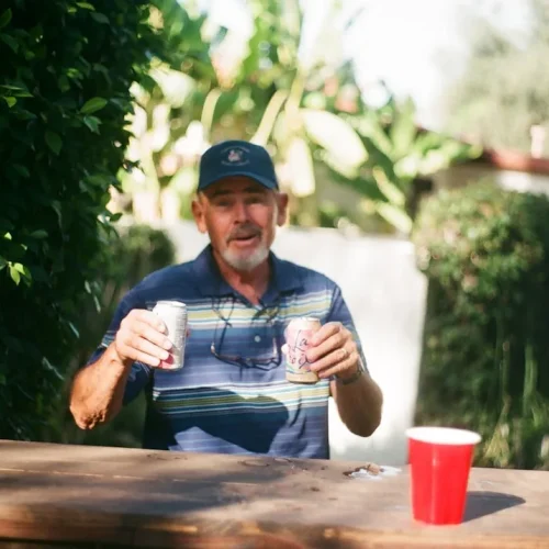 A man opening a thoughtful gift at a family gathering, illustrating the best gifts for a stepdad