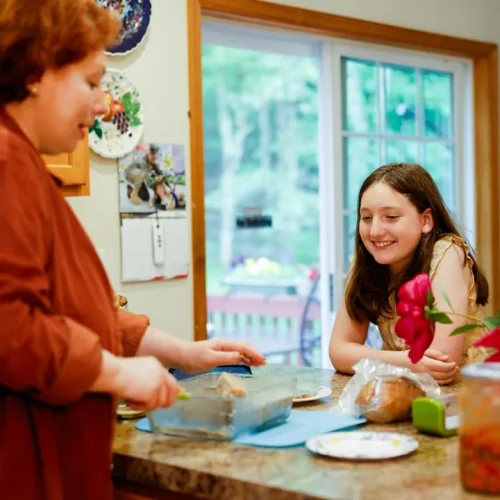 A woman receiving a thoughtfully wrapped gift at a family gathering, illustrating good gifts for a stepmom