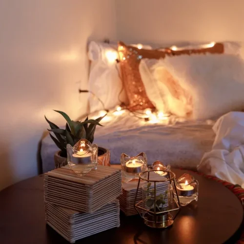 Cosy living room corner with chunky knit blanket, sheepskin slippers, and warm ambient lighting—perfect homebody comfort essentials