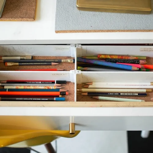 Neatly organised desk setup with bamboo drawer dividers, brass pencil cup, and leather cable organiser