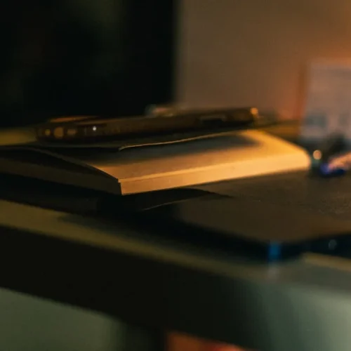 Curated stationery collection featuring fountain pen, quality notebook, and brass desk accessories on wooden surface