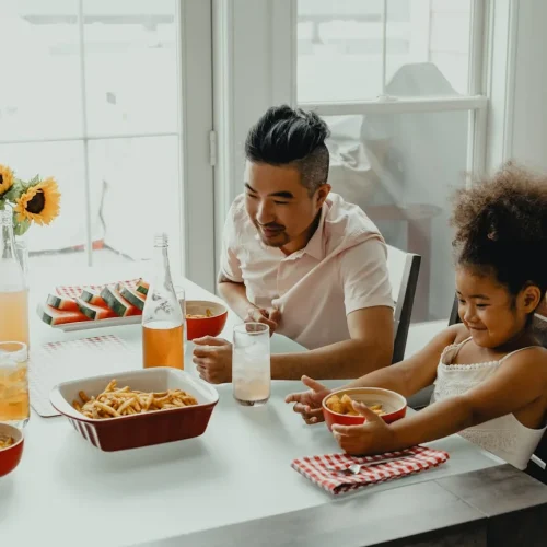 A father opening a gift at a family dinner, illustrating good gifts for your girlfriend's dad