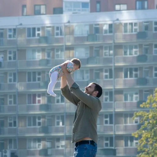 A new father holding his baby at home, illustrating good gifts for your husband after becoming a dad