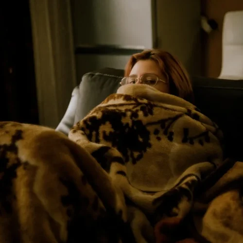 A person resting quietly on a sofa under a blanket, illustrating gifts for your partner after a hard month