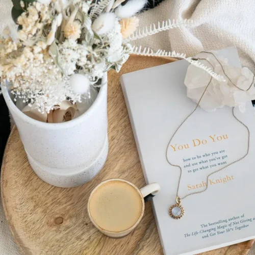 A collection of personalised sentimental gifts including a star map, engraved jewellery, and a handwritten letter book arranged on a wooden surface