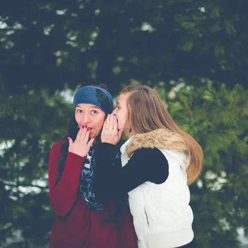 Two people sharing a secret conversation about gift planning with thoughtful expressions