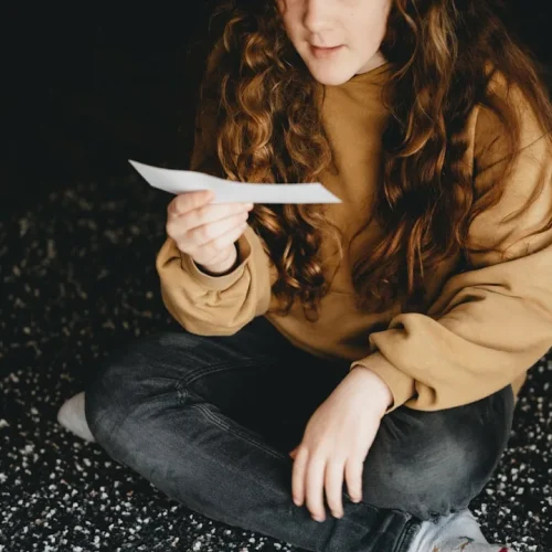 Woman reading a heartfelt handwritten letter, visibly moved by the thoughtful personal gift" } ```