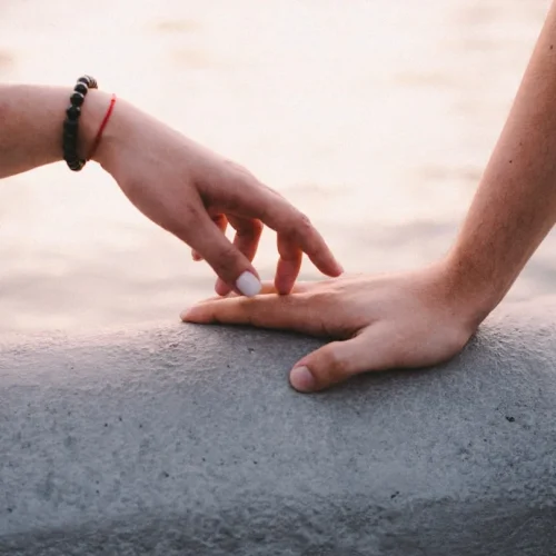 Hands reaching toward each other through a computer screen, symbolizing connection and sentimental gifts for long-distance relationships
