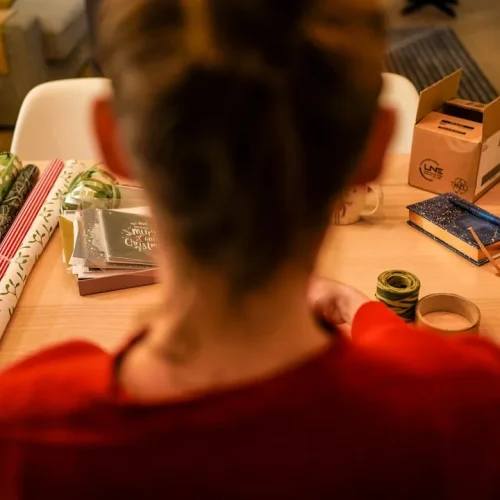 Person considering multiple wrapped gift options with thoughtful expression
